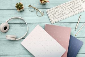 Woman home office desk workspace with laptop, headphones cactus in pastel blue wooden. Flat lay, top view. stylish female concept